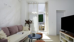 Una sala de estar moderna con un sofá, una mesa de centro, un televisor y un comedor con sillas y una mesa.