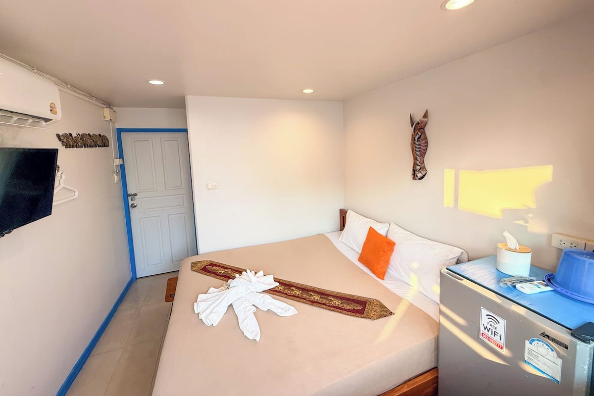 Habitación de hotel con cama, televisión, escritorio y computadora, y un calentador de pared.