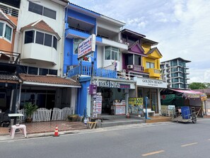 A multi-story hotel with balconies, a signboard, and a storefront with a signboard. - Kelly Hotel Bangsaen (Mueang Chonburi)