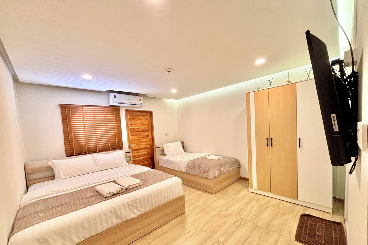 Un dormitorio con dos camas, un armario, un televisor y un equipo de aire acondicionado.