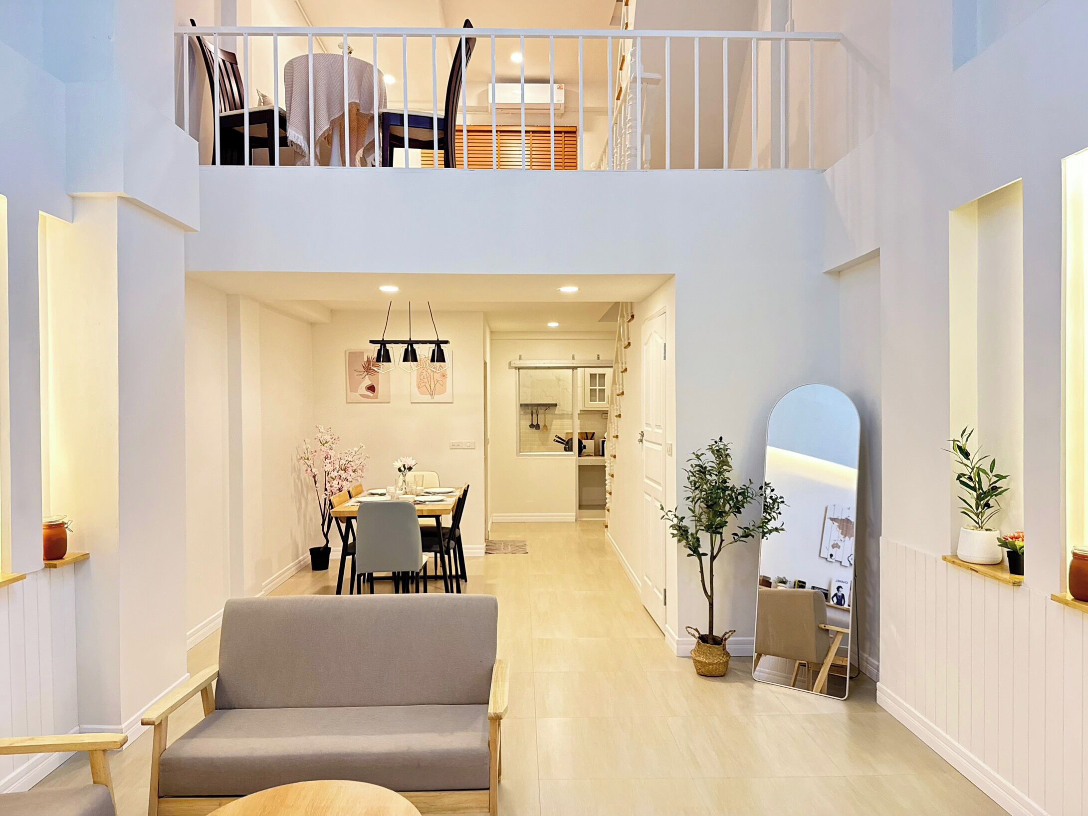 A spacious interior with a dining area, a sofa, a staircase, and a mirrored wall.