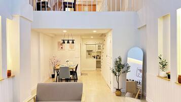 A spacious interior with a dining area, a sofa, a staircase, and a mirrored wall.