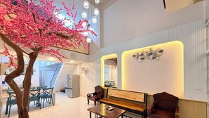 Un vestíbulo espacioso con un gran árbol artificial, zona de estar y un moderno mostrador de recepción.