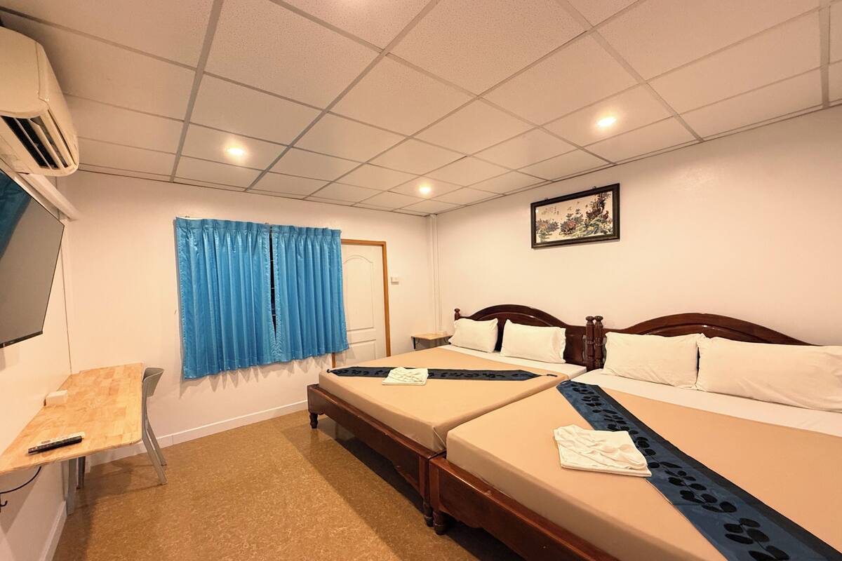 Habitación de hotel con dos camas, un escritorio, una silla, un televisor y una puerta.