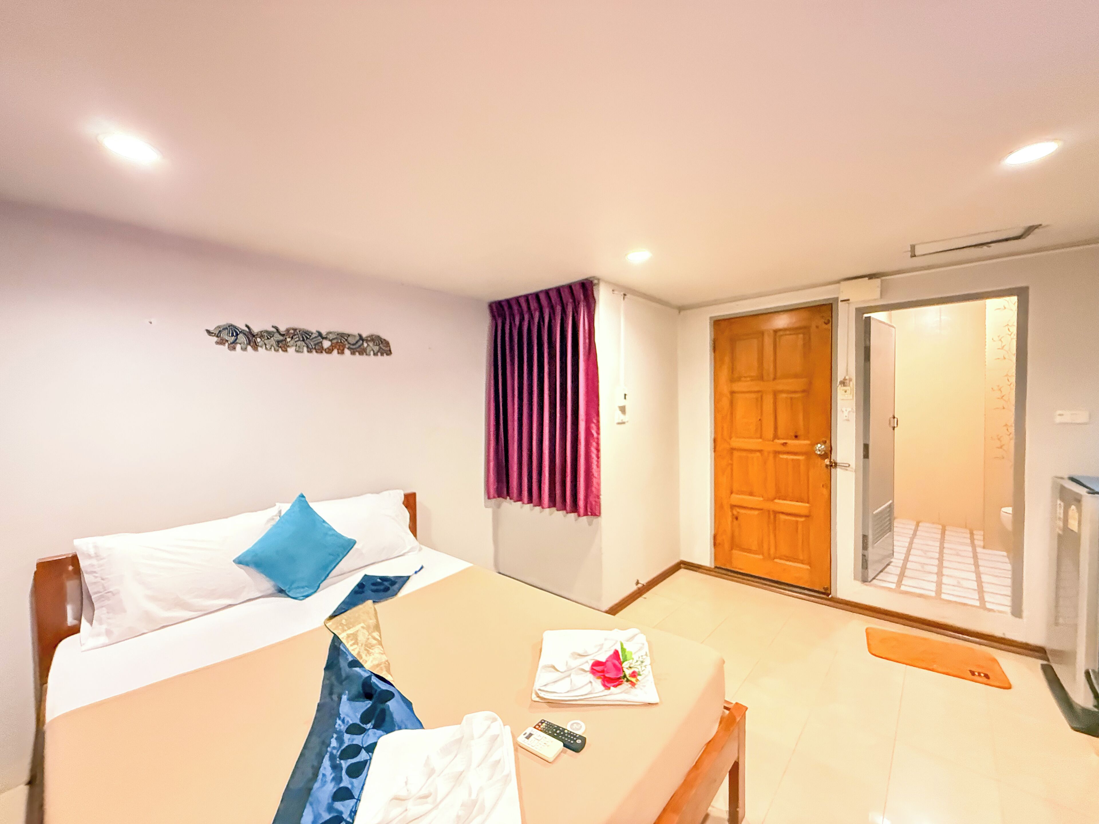Ein Hotelzimmer mit Bett, Tisch, Duschbereich und einer Tür zum Badezimmer.