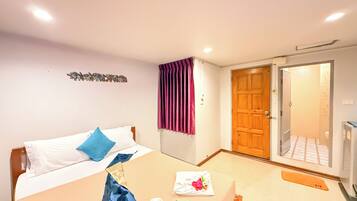 Ein Hotelzimmer mit Bett, Tisch, Duschbereich und einer Tür zum Badezimmer.