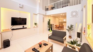 Un amplio espacio de sala con televisión de pantalla plana, un sofá, una mesa de comedor y un balcón.