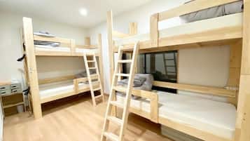 A room with bunk beds, a ladder, and a desk with drawers.