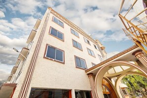 A multi-story building with a beige facade, large windows, and a central entrance with an archway. - SRS Jade Empire (Anekal)