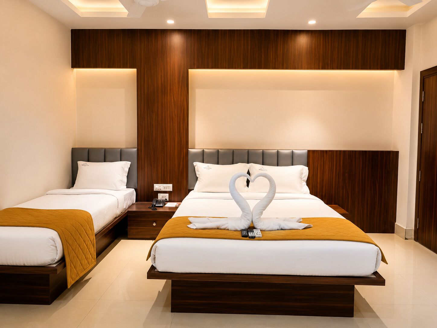 Habitación de hotel con dos camas, cabecera de madera, mesita de noche y un cisne decorativo sobre la cama.