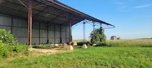 A large metal barn with a covered porch, surrounded by a grassy field and a clear sky. - The Gîte de Préaux: a single-story house with 3 bedrooms (sleeps 6) (Tousson)