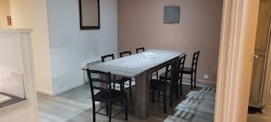 A dining area with a rectangular table, six chairs, a decorative centerpiece, and a Buddha statue on the wall. - The Gîte de Préaux: a single-story house with 3 bedrooms (sleeps 6) (Tousson)