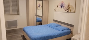 A bedroom with a bed, a wardrobe, a window with blinds, and a wall-mounted artwork. - The Gîte de Préaux: a single-story house with 3 bedrooms (sleeps 6) (Tousson)