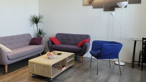 Ett vardagsrum med en soffa, en fåtölj, ett soffbord och en blå stol.