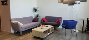A living room with a sofa, armchair, coffee table, and a blue chair. - The Gîte de Préaux: a single-story house with 3 bedrooms (sleeps 6) (Tousson)