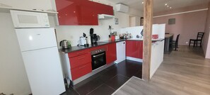 A compact kitchen with red and white cabinetry, a microwave, a coffee maker, and a dishwasher. - The Gîte de Préaux: a single-story house with 3 bedrooms (sleeps 6) (Tousson)