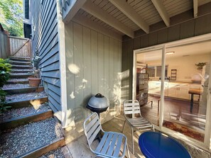 A patio with steps leading to a door, a grill, and two metal chairs. - Backyard Studio Near Lake WA, UW, & Hospitals (Seattle)