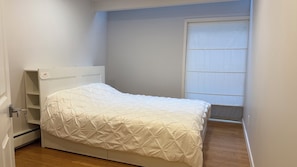 Una cama pequeña y bien hecha con cabecera blanca y diseño sencillo y limpio.