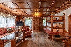 Ein Holzblockhaus-Innenraum mit einer Couch, einer Bank, einem Holztisch und einem Fernseher.