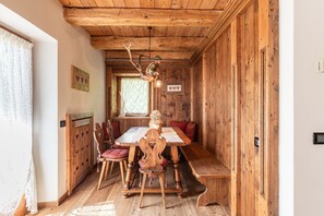 Ein Esszimmer mit Holzboden, einem Tisch, Stühlen, Bänken und einer Hängeleuchte.