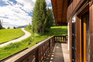 Ein hölzerner Balkon mit Blick auf eine kurvenreiche Straße und grüne Landschaft.