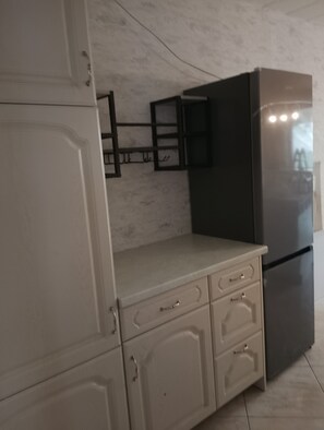 Une cuisine avec un réfrigérateur noir, des armoires de couleur beige et un pare-feu en marbre.
