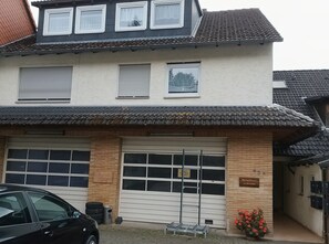 Een gebouw met twee verdiepingen, een garage, een bord dat op een bedrijf wijst en een bloempot.