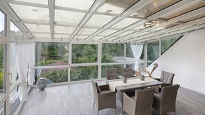 A conservatory with a glass ceiling, wicker furniture, and a view of greenery. - Holiday Apartment An Der Lempe with Wi-Fi (Hofgeismar)