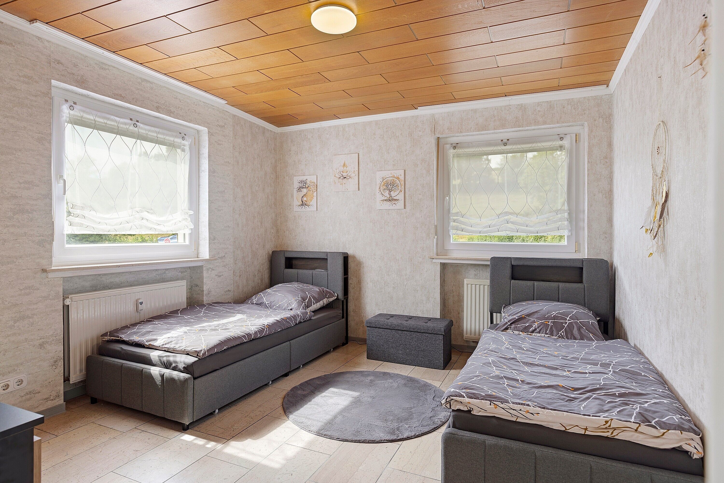 Ein Schlafzimmer mit zwei Einzelbetten, einem kleinen runden Teppich und einem Fenster mit Blick.