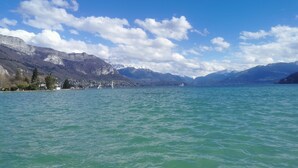 Un llac amb muntanyes al fons, cel serè i uns quants vaixells a l'aigua.