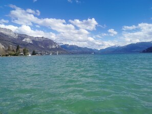 Ein See mit Bergen im Hintergrund, ein klarer Himmel und einige Boote auf dem Wasser.