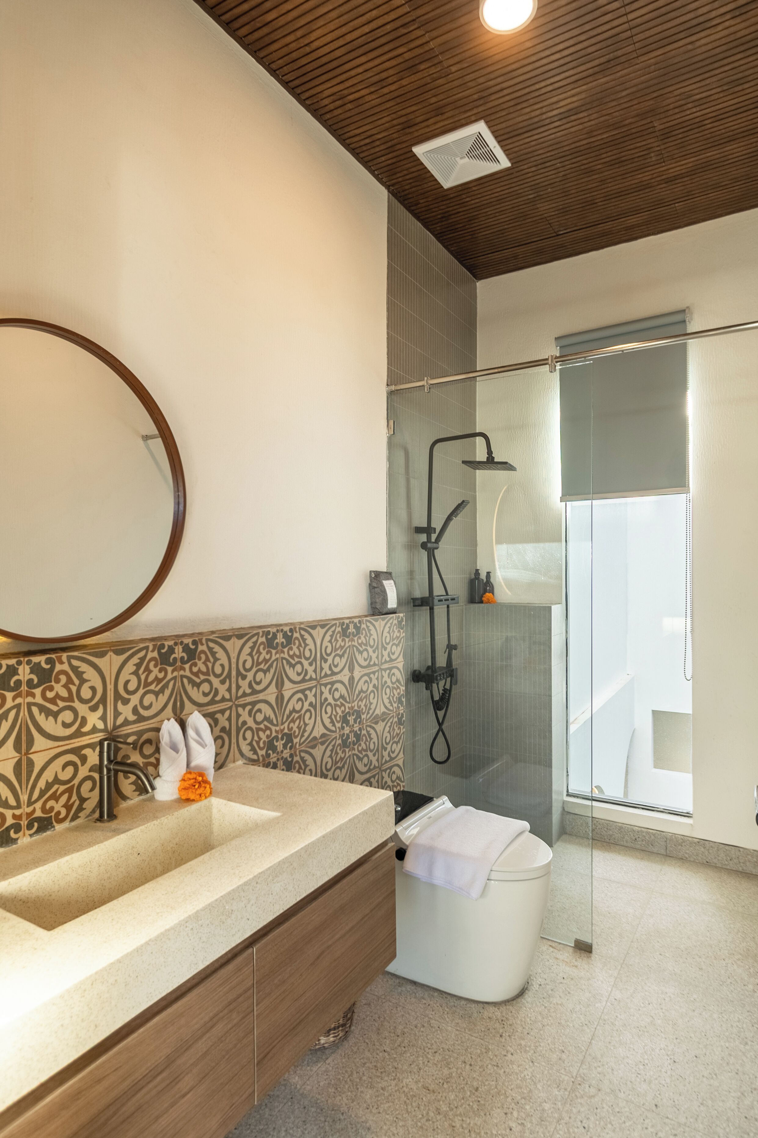 A modern bathroom with a large sink, a mirror, a shower, and a toilet.