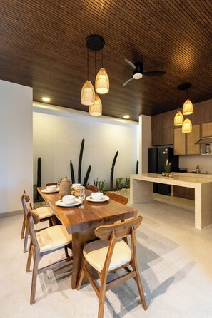 A modern kitchen with a central island, wooden chairs, and pendant lights. - Uluwatu 2 Bedrooms villa with Rooftop (Kec. Kuta Sel)
