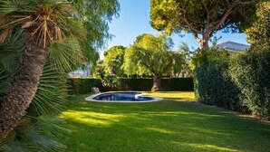 Ein gepflegter Garten mit Swimmingpool, umgeben von üppiger Vegetation und Bäumen.