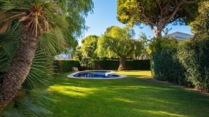 Un jardin bien entretenu, doté d’une piscine, et entouré d’une végétation luxuriante et d’arbres.
