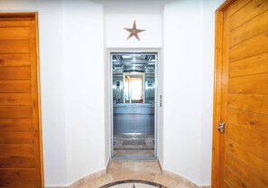 A hallway with wooden doors, a star decoration, and an elevator. - Tessoro #1002 at Las Conchas – Elevated Luxury on the Sea of Cortez (Puerto Peñasco)
