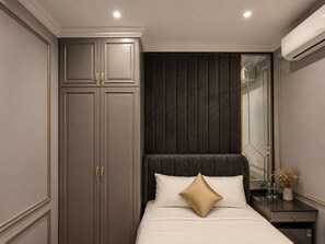 A bedroom with a bed, a wardrobe, a mirror, and a nightstand. - D'Élite Boutique Hotel Dĩ An (Di An)