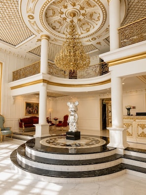 A grand lobby with a central chandelier, marble flooring, and a statue labeled 'Supreme.' - D'Élite Boutique Hotel Dĩ An (Di An)