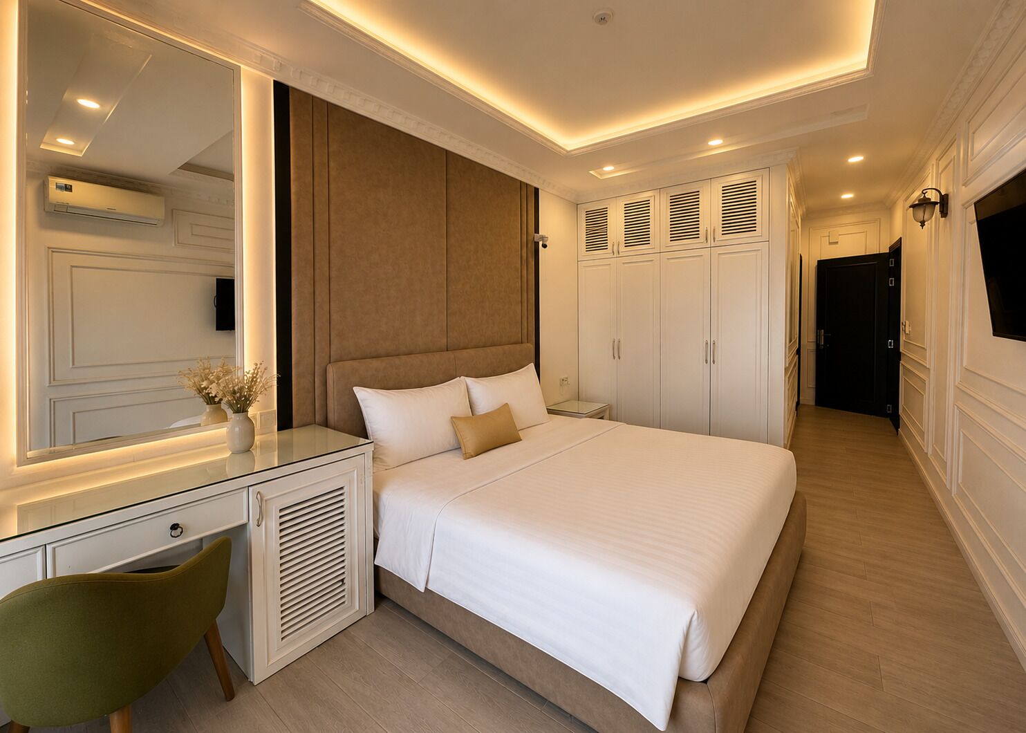 A bedroom with a large bed, a bedside table, a mirror, a wardrobe, and a TV.