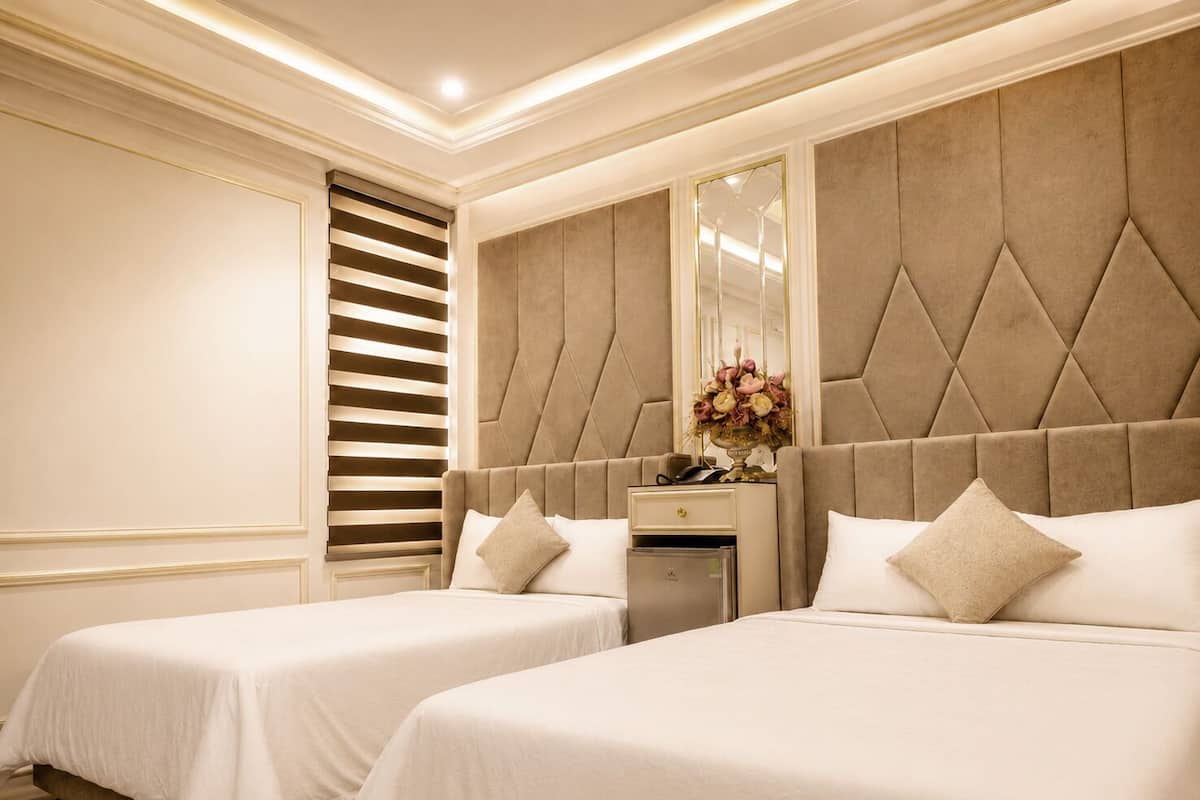 A hotel room with two beds, a dresser, a mirror, and a window with blinds.