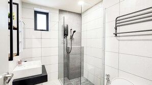 Ein modernes Badezimmer mit einer Duschkabine aus Glas, einem weißen Waschbecken und einer Toilette.