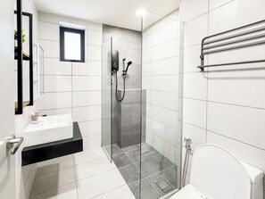 Ein modernes Badezimmer mit einer Duschkabine aus Glas, einem weißen Waschbecken und einer Toilette.