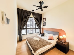 Ein Hotelzimmer mit einem Bett, einem Nachttisch mit Lampe, einem Deckenventilator und einem Fenster mit Vorhängen.