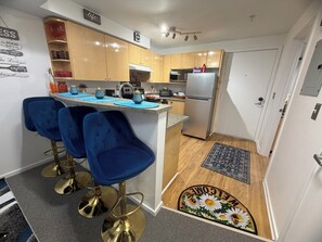 Una cocina moderna con armarios de madera, una isla central con taburetes de bar, un refrigerador y un microondas.