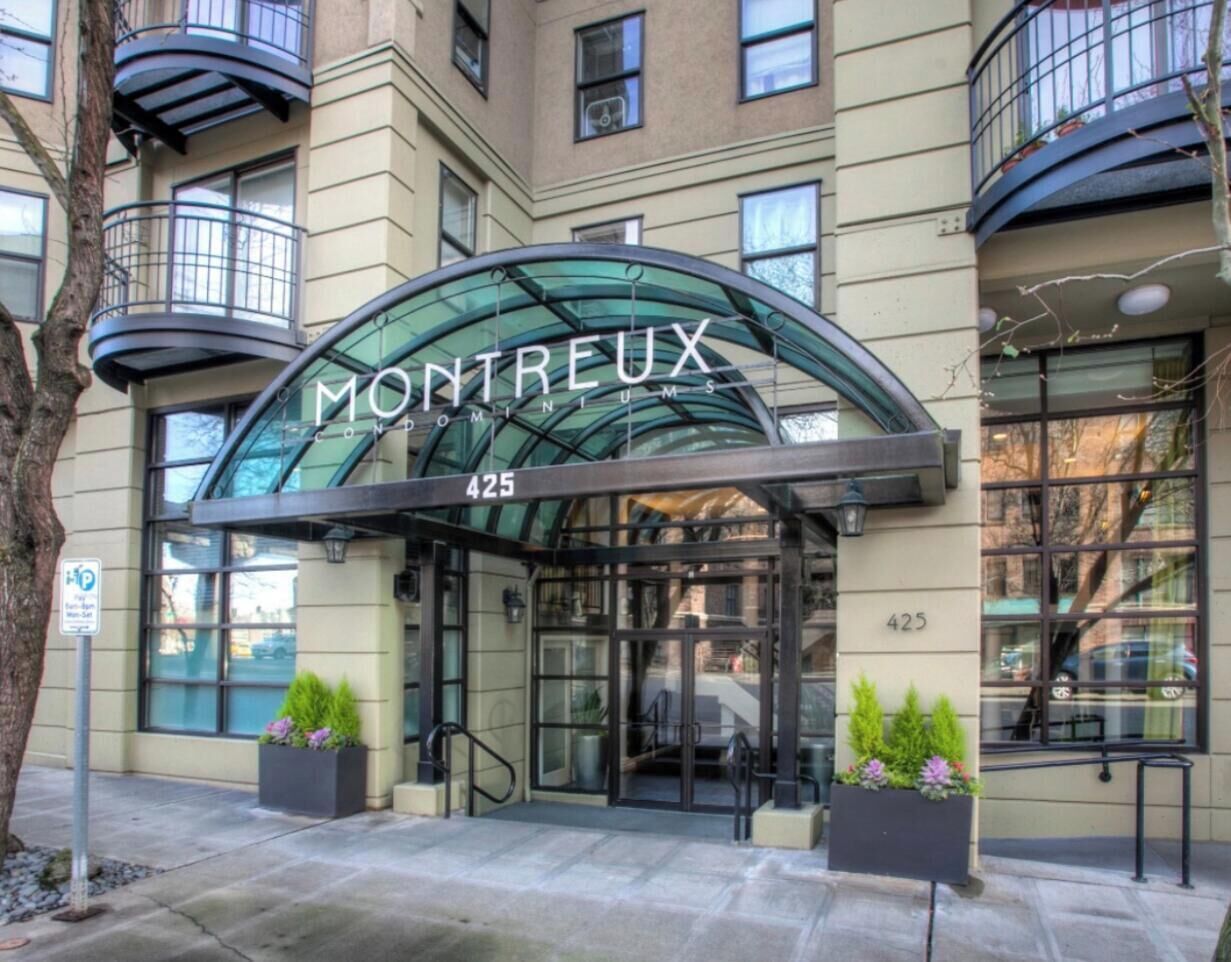 A hotel entrance with a glass canopy, a number '425' sign, and potted plants.