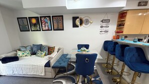 Un salon moderne avec un canapé, une table à manger et des tabourets de bar bleus.