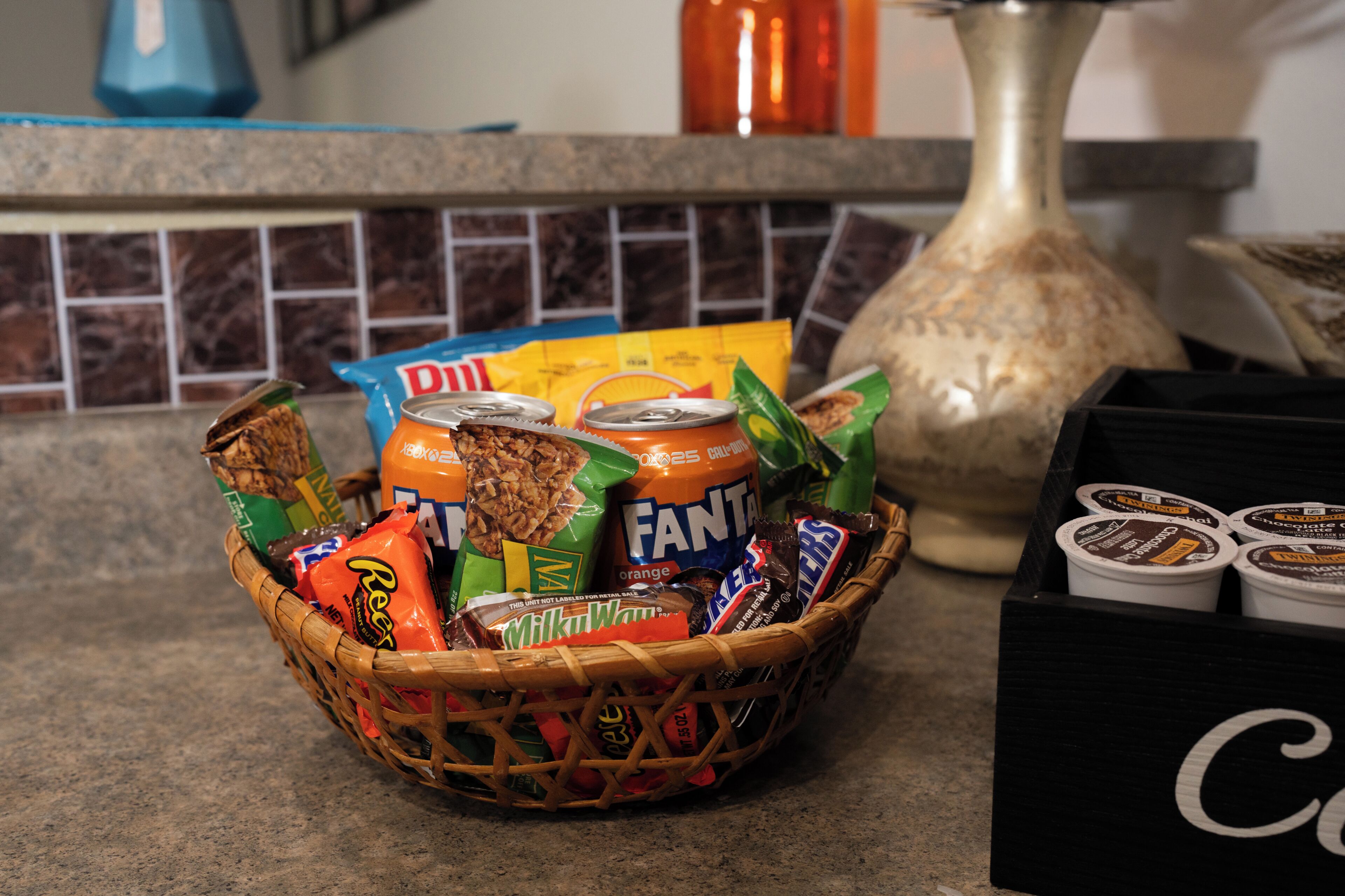 Eine Korb mit Snacks und eine Packung Instantkaffee auf einer Küchenarbeitsplatte.