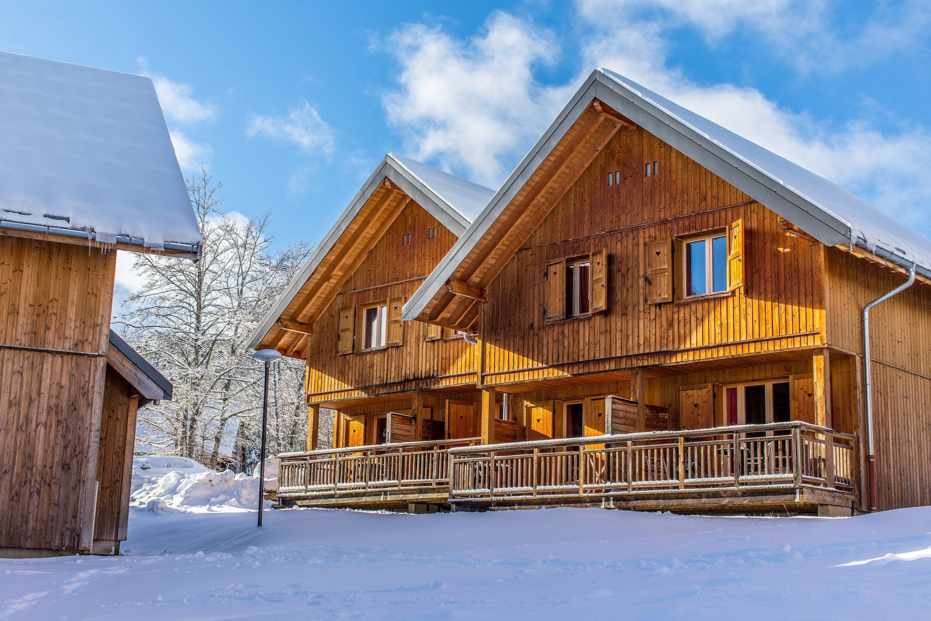 A wooden cabin with a balcony and a snow-covered roof.
