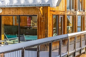 Ein Holzhaus mit großen Fenstern und einem Balkon mit Schnee.