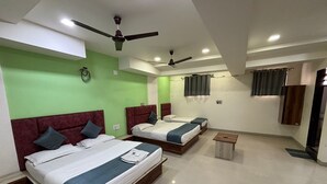 A hotel room with two beds, a ceiling fan, a small table, and a mirror. - HOTEL VIVANTA (Ahmedabad)